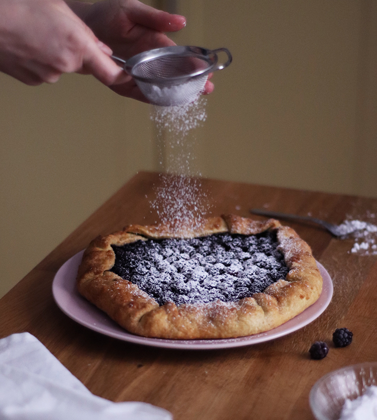 Saupoudrage de sucre glace sur la tarte rustique aux mûres